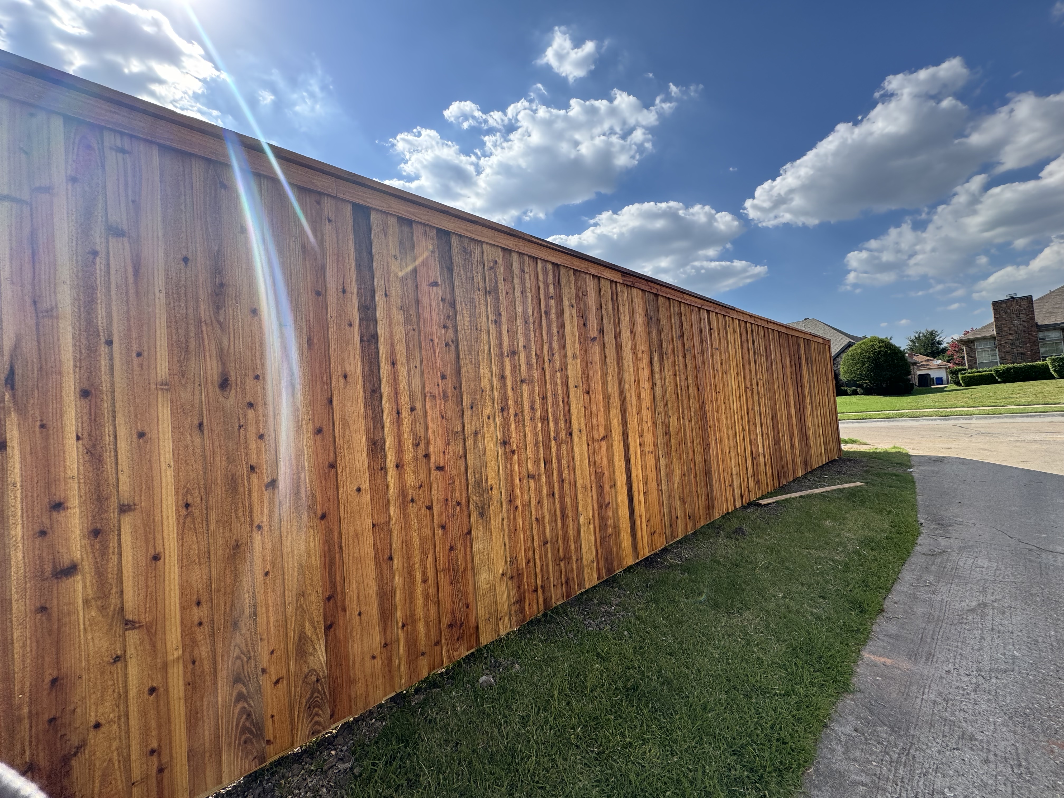 "A recently installed 8ft board-on-board vertical cedar fence showcasing its rich color and natural grain, providing privacy and enhancing the outdoor aesthetic
